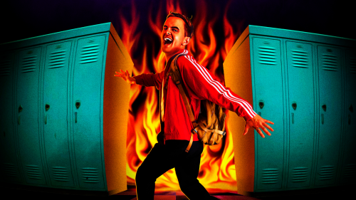 A white man with blonde hair wearing a red athletic jacket, black trousers and a yellow rucksacks turns back towards the camera with a devilish, open mouthed smile. Behind him is a row of blue American school lockers with fire filling a gap between them.