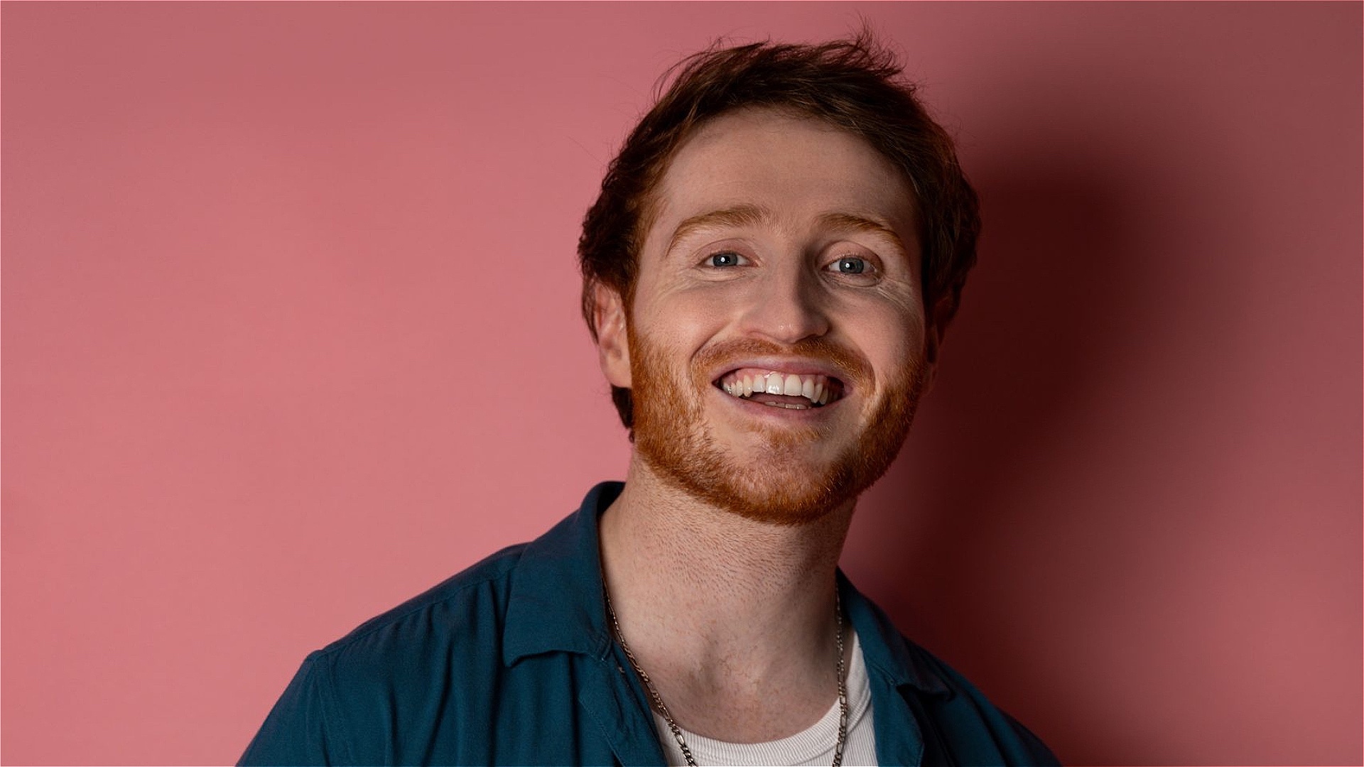 Ginger man with a blue shirt on a pink background 