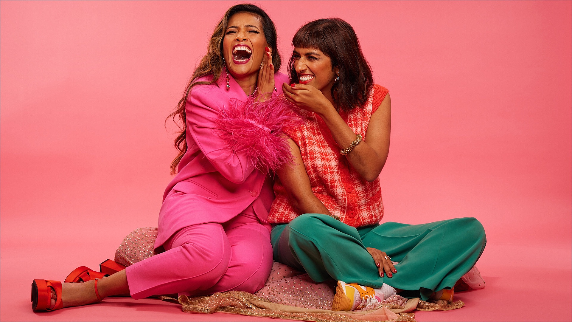 Two women, colourfully dressed, laugh at a shared joke