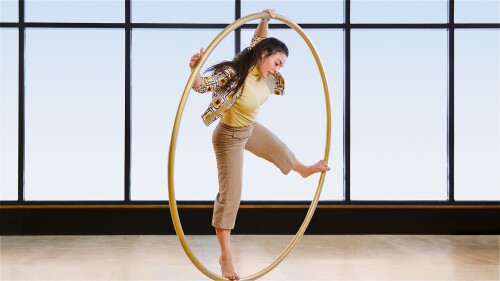 A performer in a cyr wheel is standing against a light background