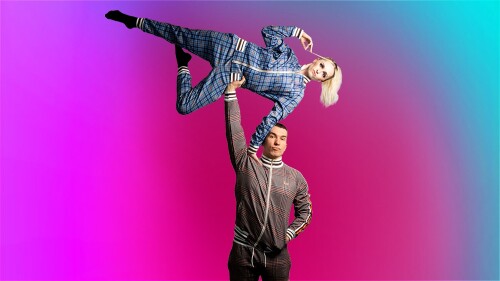 One man stands legs akimbo, arms open, he stares into the darkness. Above him a woman is suspended in the air. Separately they are just 2 people in funny positions, together they are circus.