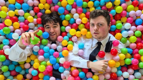 Two men in prison officer uniform, in a multi-coloured ball pit