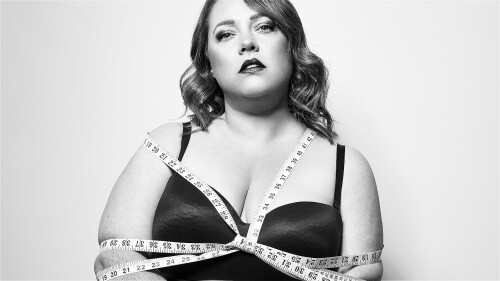 A woman is tied up with a tape measure longingly looking into the camera