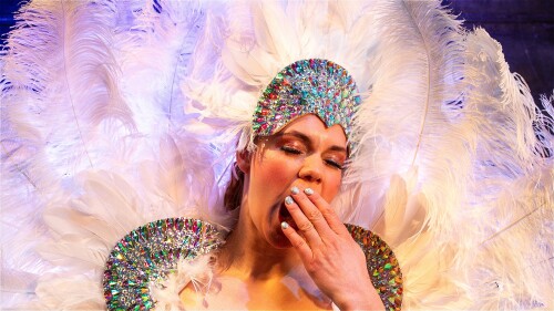 Karen, dressed up in white feathers, yawns. Crash of the expectations of a 