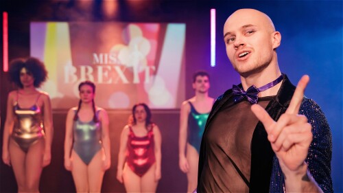 A flamboyant MC in front of a row of four misses. The misses stand like dolls and the MC holds an intriguing pose.
