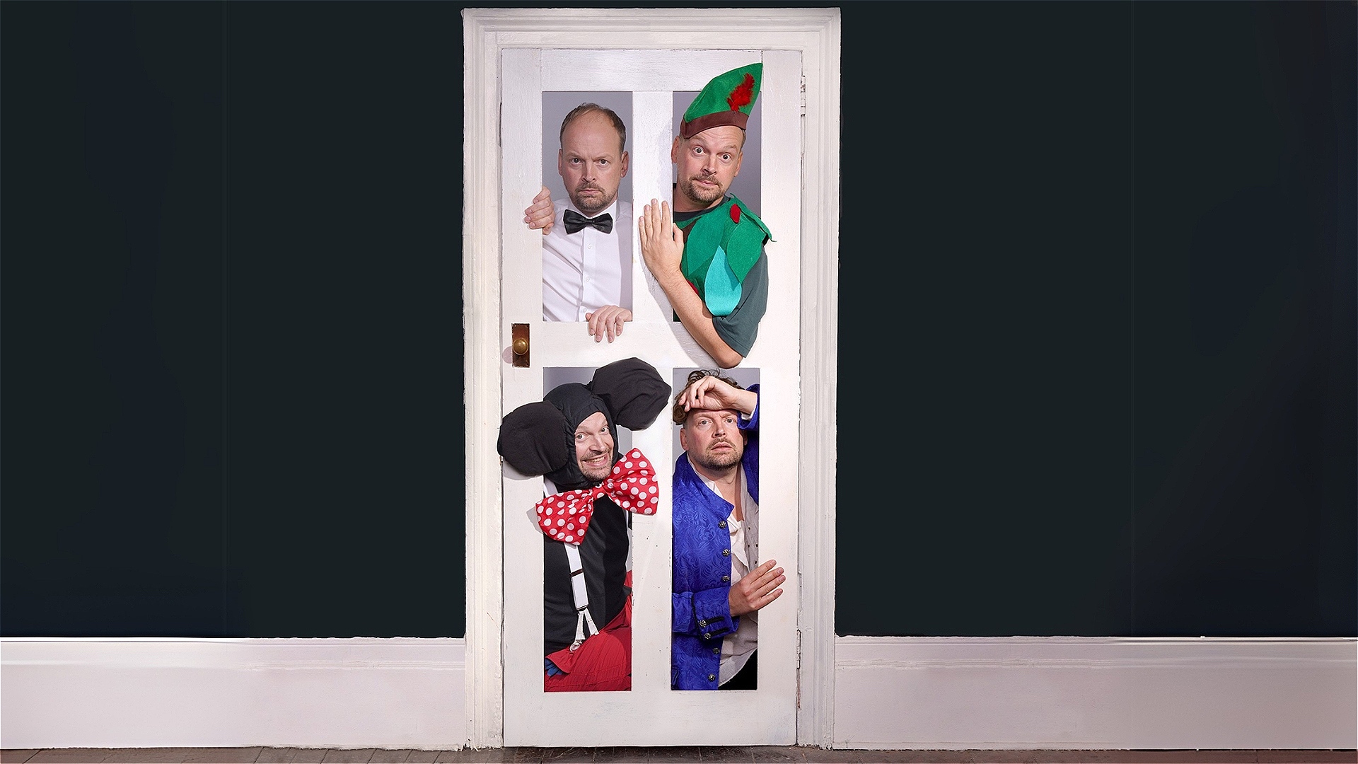 White door in the middle of a plain dark wall with white skirting running along bottom of the wall. The door has four panels with performer Neil Frost in four different costumes. Top left door panel - white shirt and black bowtie costume, Top right door 
