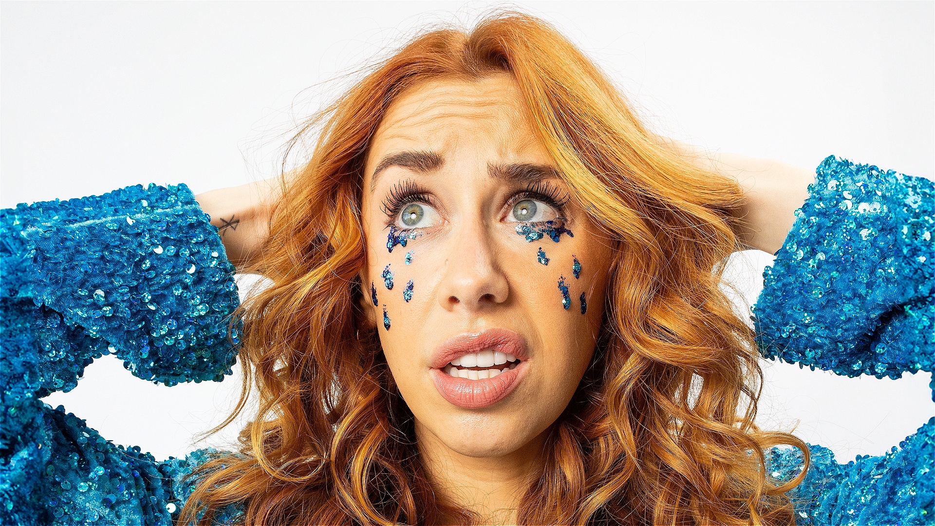 A woman cries tears made of blue glitter