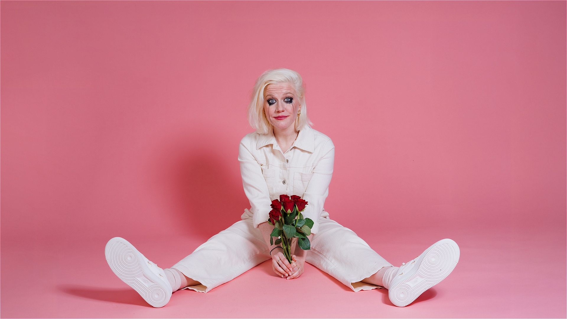 Lulu holds bouquet of roses, mascara tear stains down her cheeks, in all white.