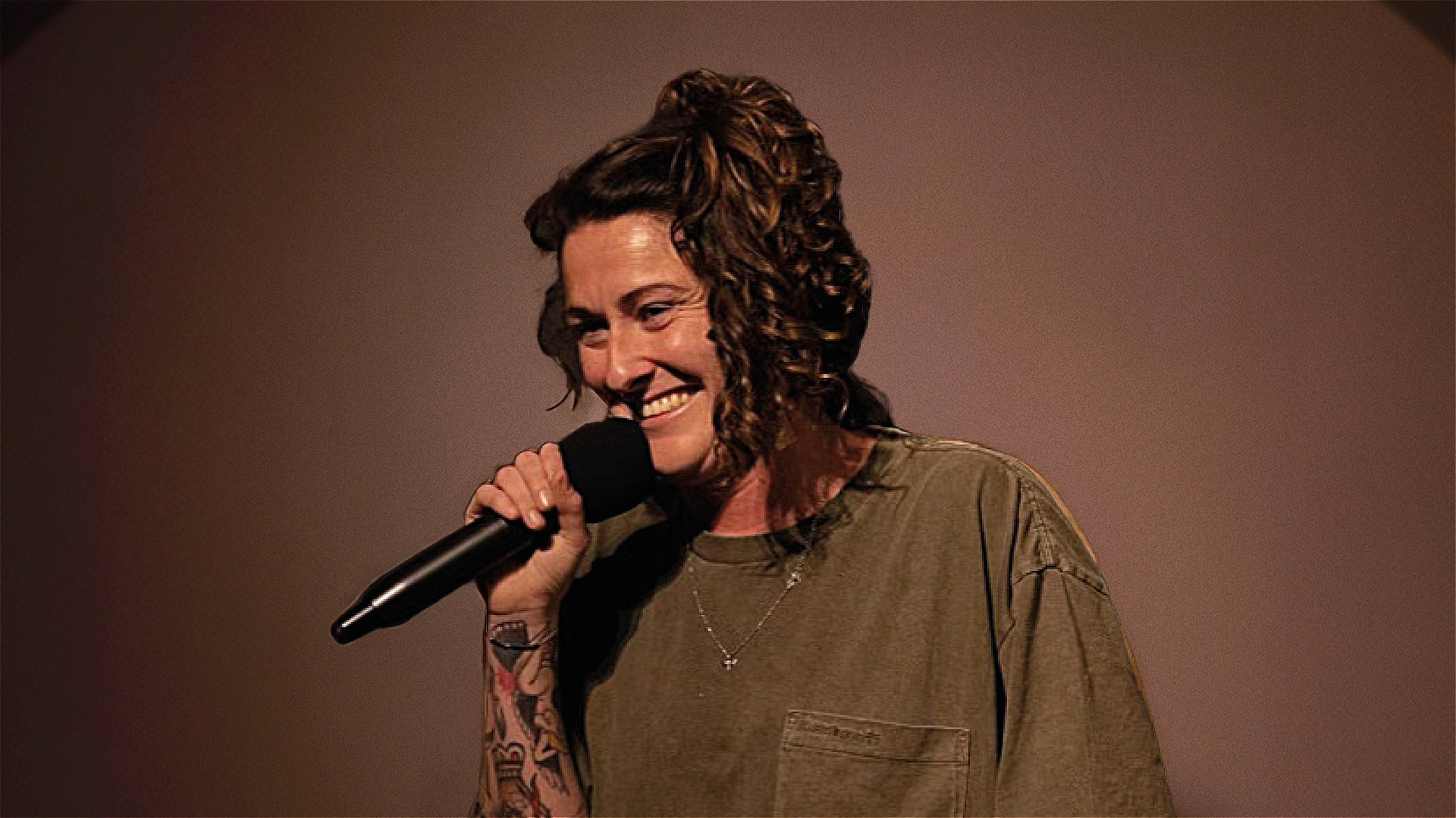 A women stands on stage with a microphone.