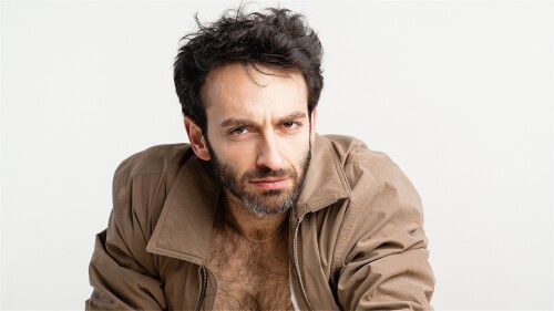An image of Gianmarco Soresi. He is wearing a light brown jacket and stares into the camera 