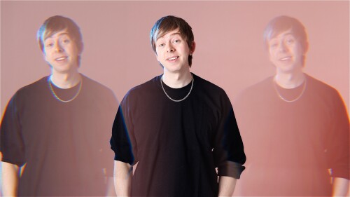 Comedian and Freestyle Rapper Chris Turner stands in front of a red background, wearing a black t shirt. He is reflected through a prism two more times.
