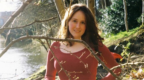 A woman standing outdoors near a river