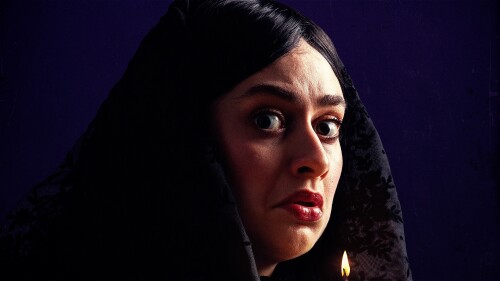 Woman mourning looks at camera and holds vigil candle.