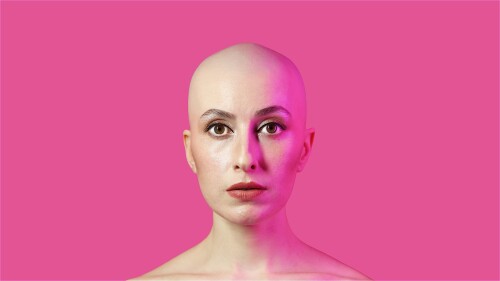 A close up of a bald woman. The background is hot pink.