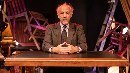 A somewhat forlorn but ultimately hopeful man sitting at a desk.