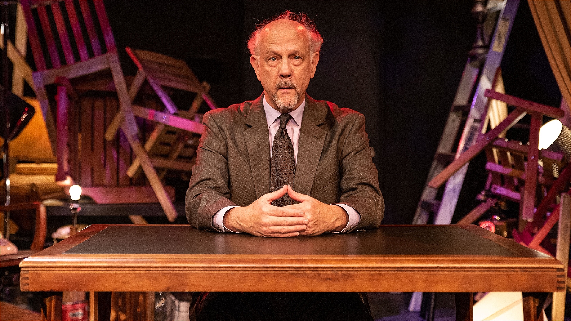 A somewhat forlorn but ultimately hopeful man sitting at a desk.