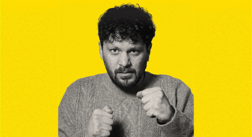 Killian Sundermann holds up his fists towards the camera against a yellow background 