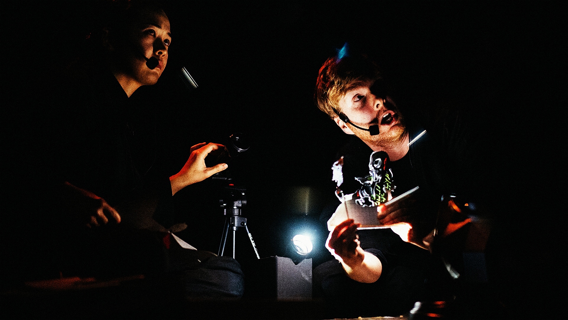 Two puppeteers operate shadow puppets.