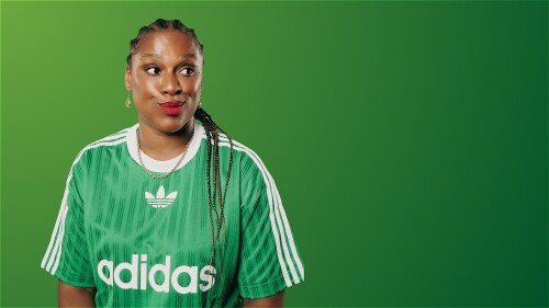 A person with braided hair in a green Adidas jersey looks off to the side with a playful expression against a gradient green background.