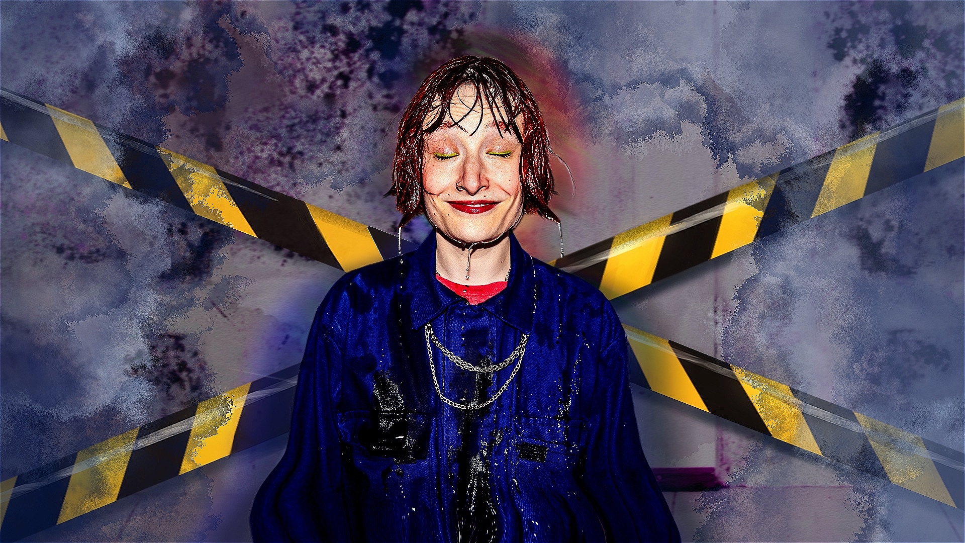 the performer, a female in their late 20s with short red hair wearing a blue boiler suit, is drenched in water. Behind them is a blue damp, mouldy wall with yellow construction tape across it