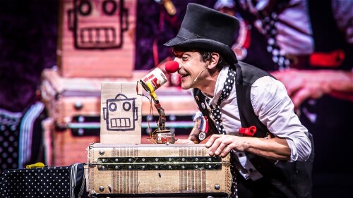 Mario the Maker Magician throws red clown noses and large balloons from stage to the kids in the audience.