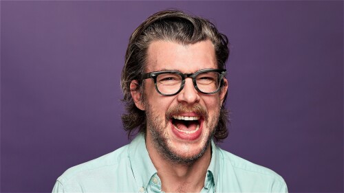 Tony Cantwell laughing in front of a purple background
