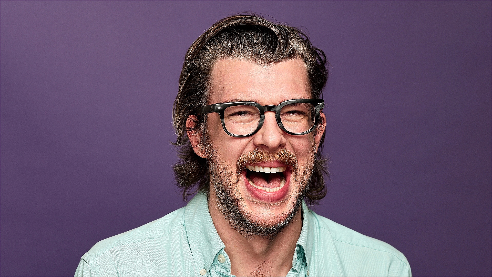 Tony Cantwell laughing in front of a purple background