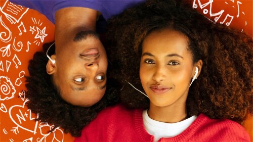 A young boy and girl are lying on the floor. The girl looks up at the viewer while the boy is looking directly at the girl. They share earphones as they listen to music. They are surrounded by illustrations of musical notes, starts, flowers and a love he