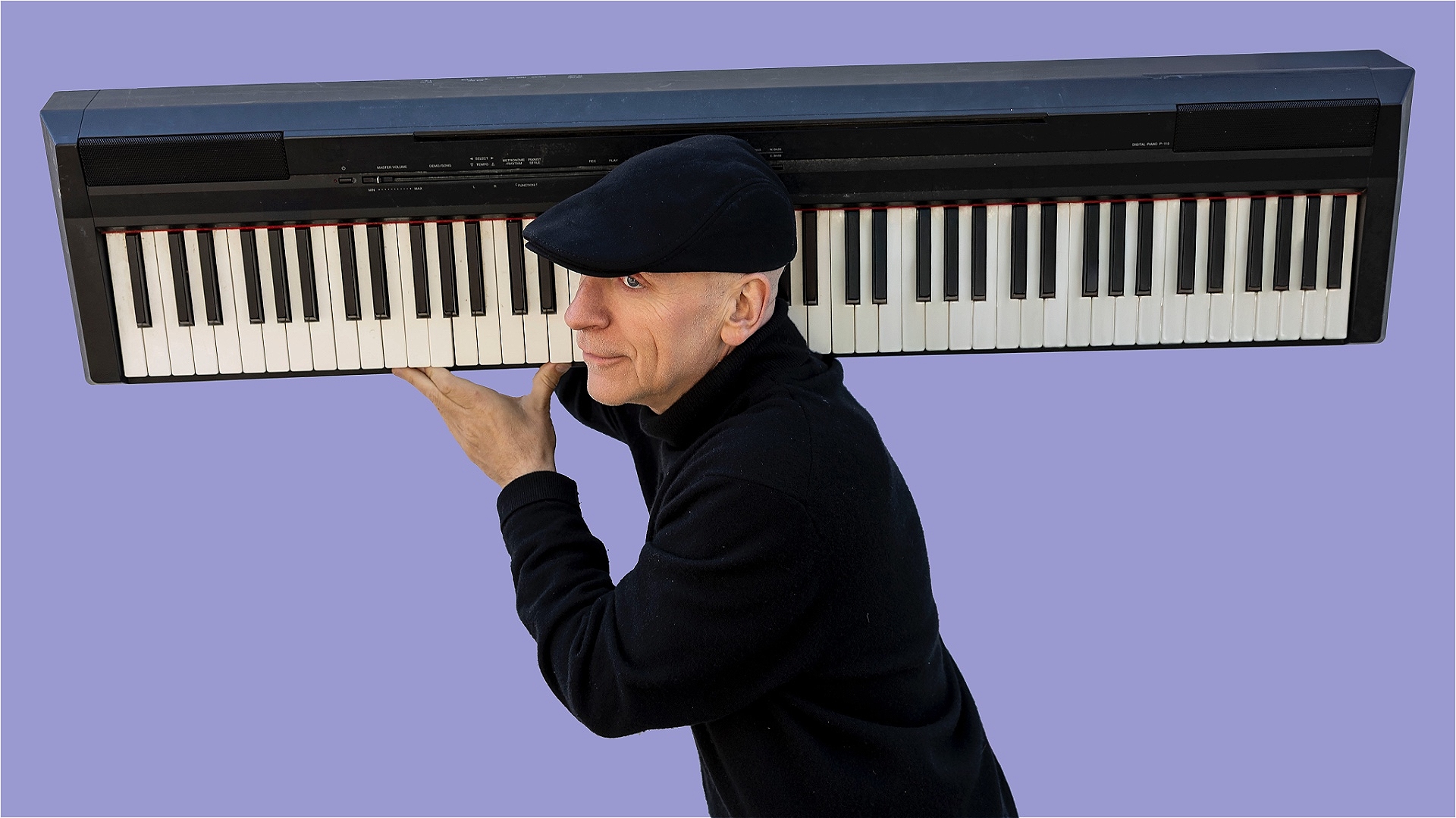 A man is furtively running with a piano on his shoulder in front of a purple background