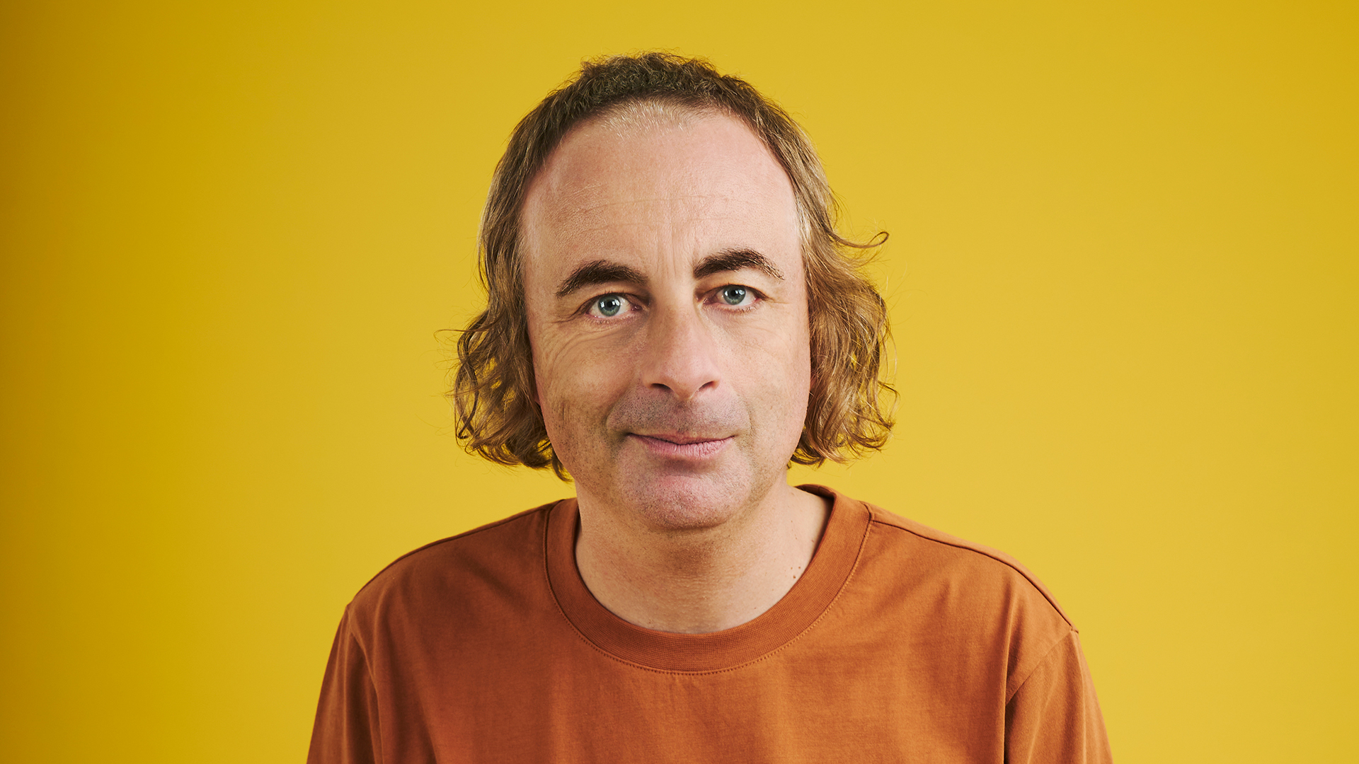 A photo of paul foot against a yellow backdrop 