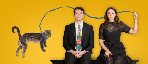 a man and a woman in black sit on a piano against a yellow background, holding the lead of a cat floating above them